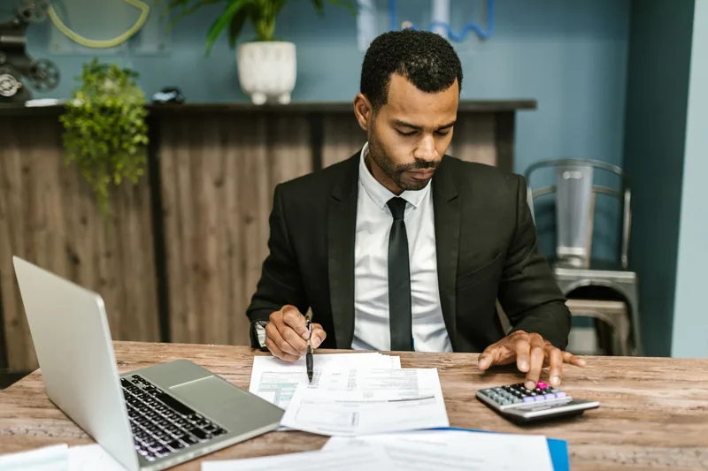 Accountant checking figures with a calculator and laptop