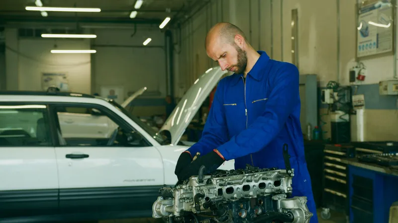 Auto mechanic in coveralls working on an engine