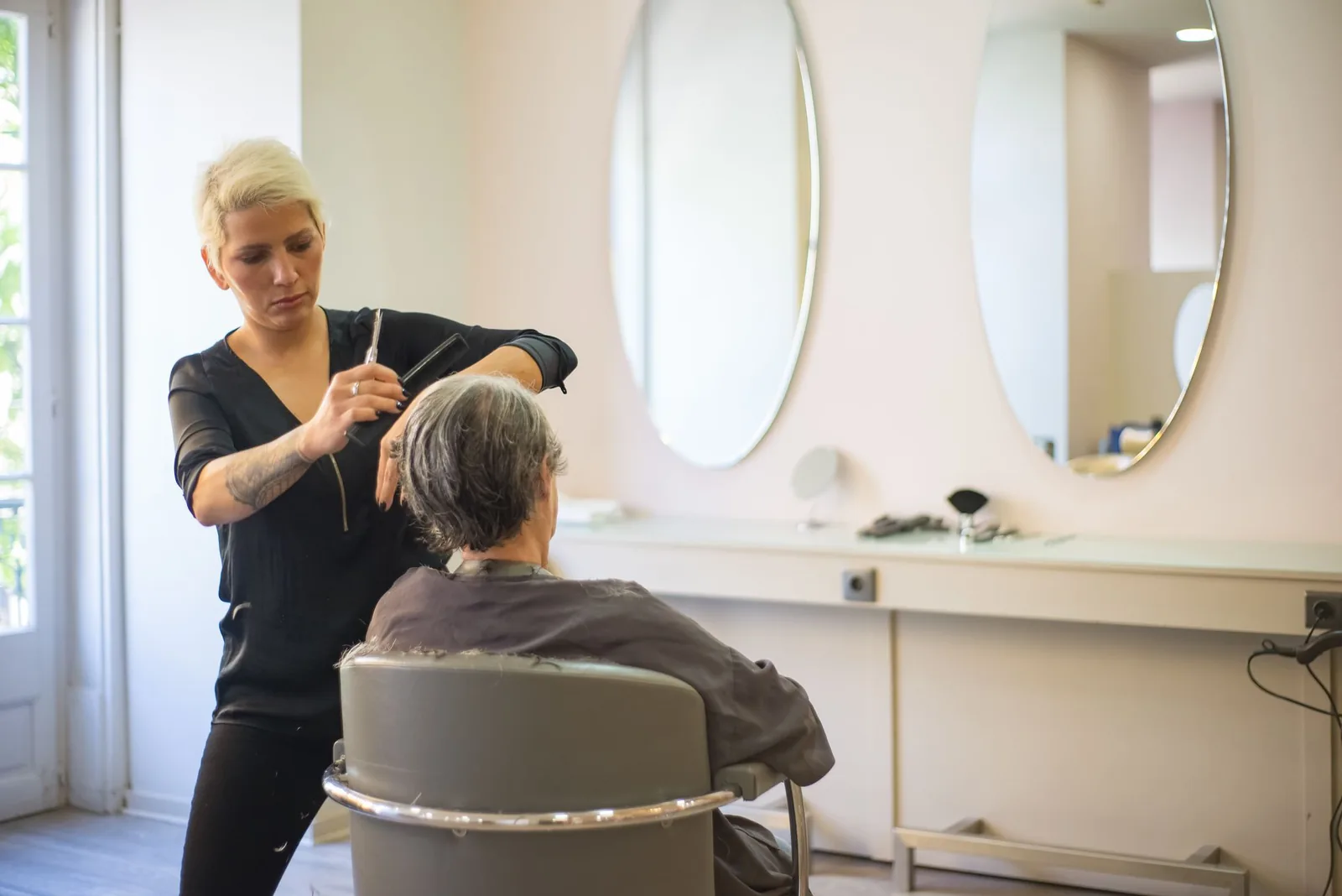 Hair stylist cutting a client's hair in a bright salon