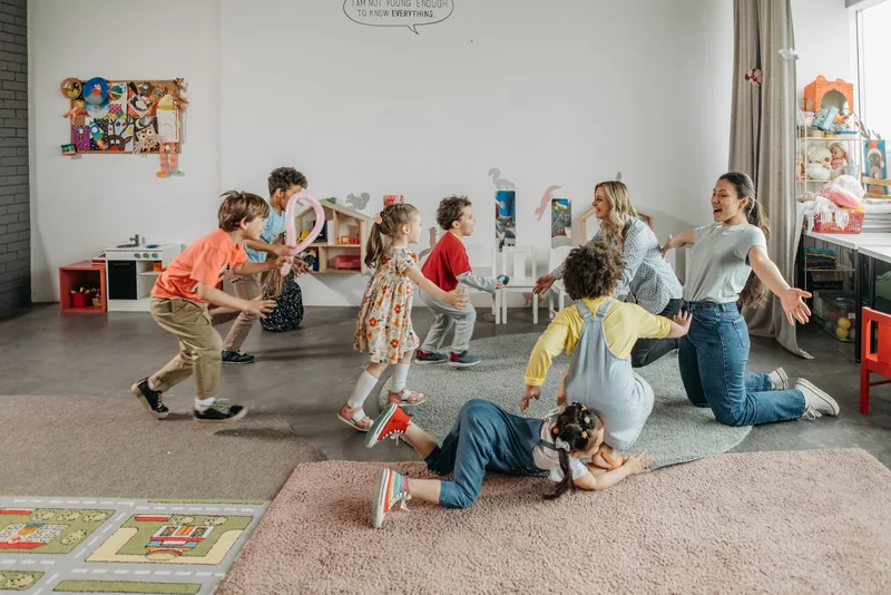 Daycare teachers playing with children in a bright classroom
