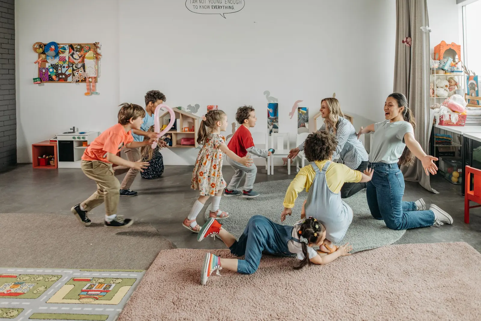 Daycare teachers playing with children in a bright classroom