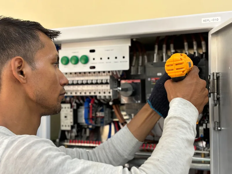 Electrician tightening connections in a breaker panel