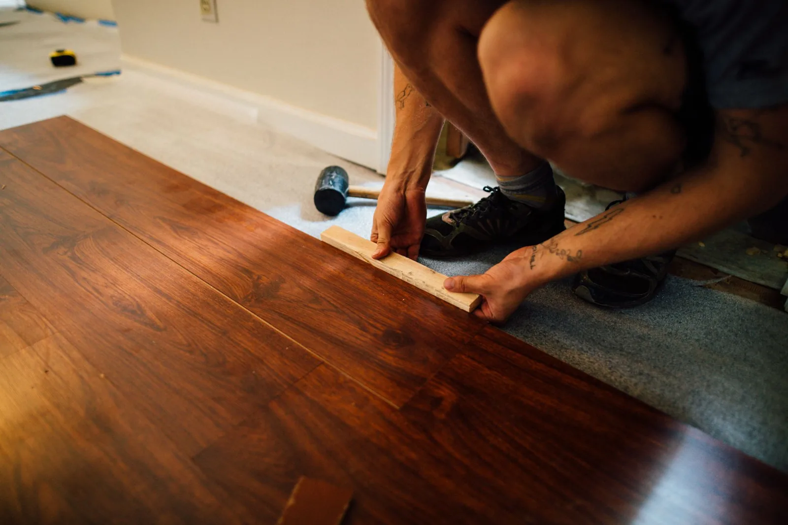 Flooring installer laying laminate planks with a mallet