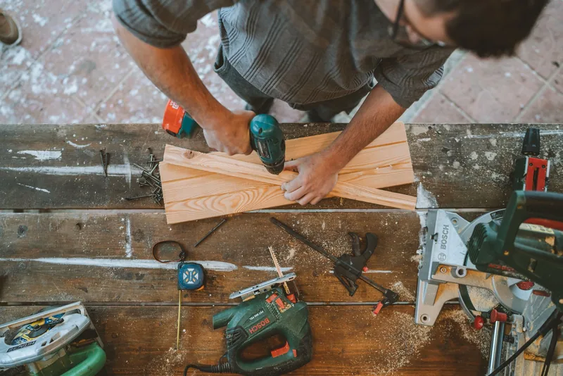 Craftsman drilling wooden planks in a workshop