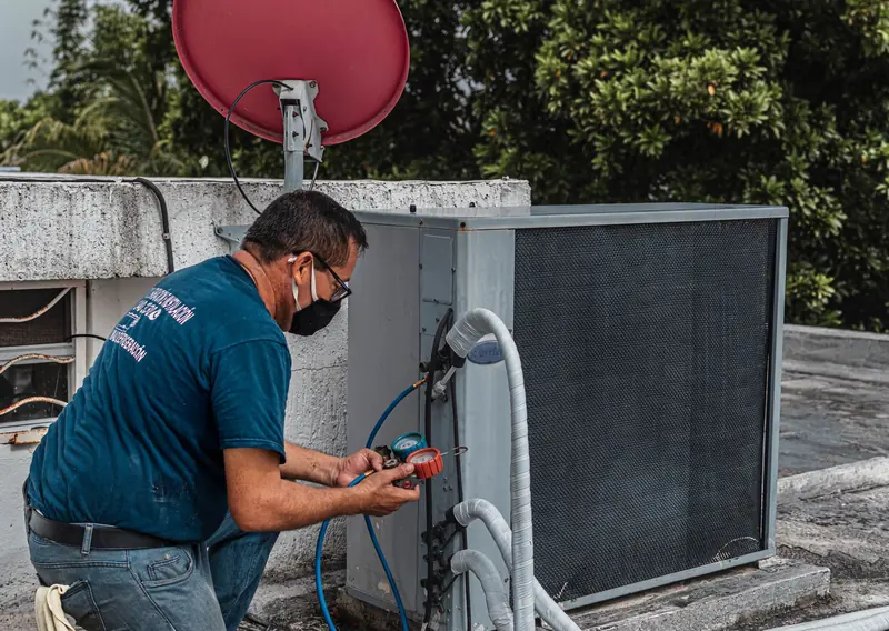 Technician checking refrigerant gauges on an air conditioner