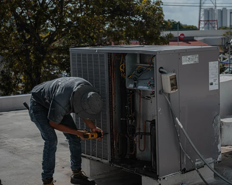 Technician working on an air conditioner casing with a drill