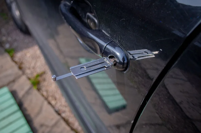 Locksmith using a pick tool on a car door lock
