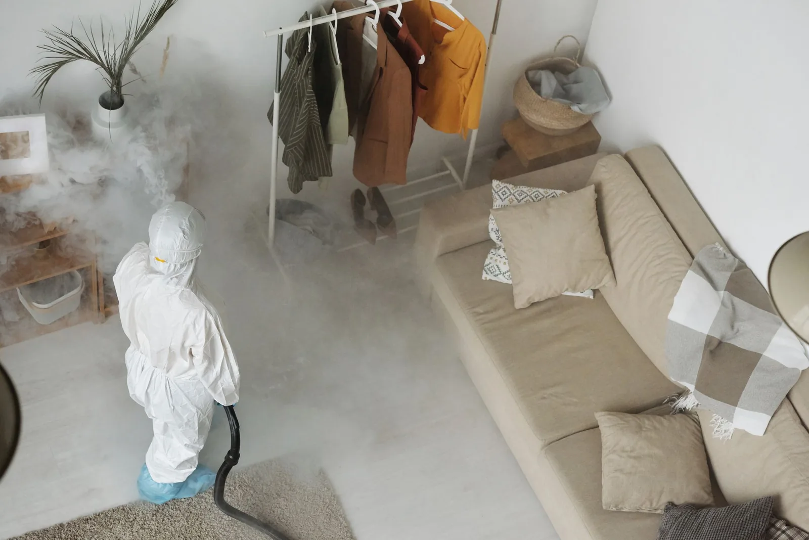 Pest control technician in a protective suit treating a living room