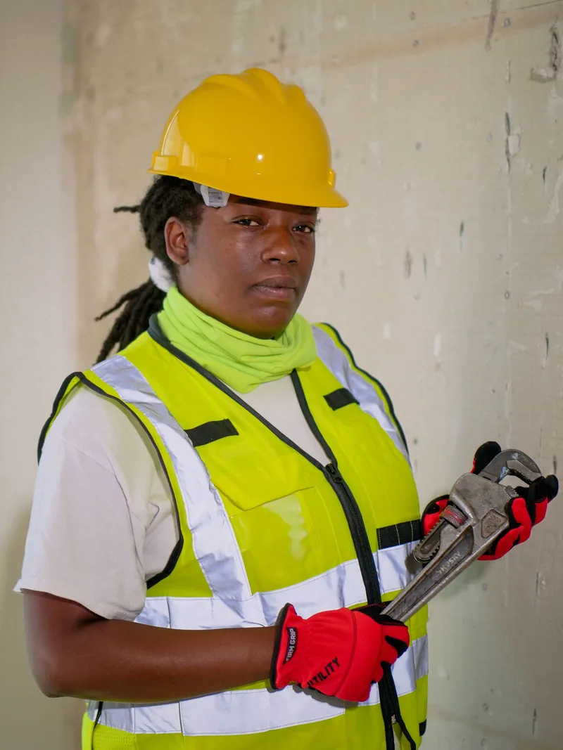 Plumber in a safety vest holding a pipe wrench