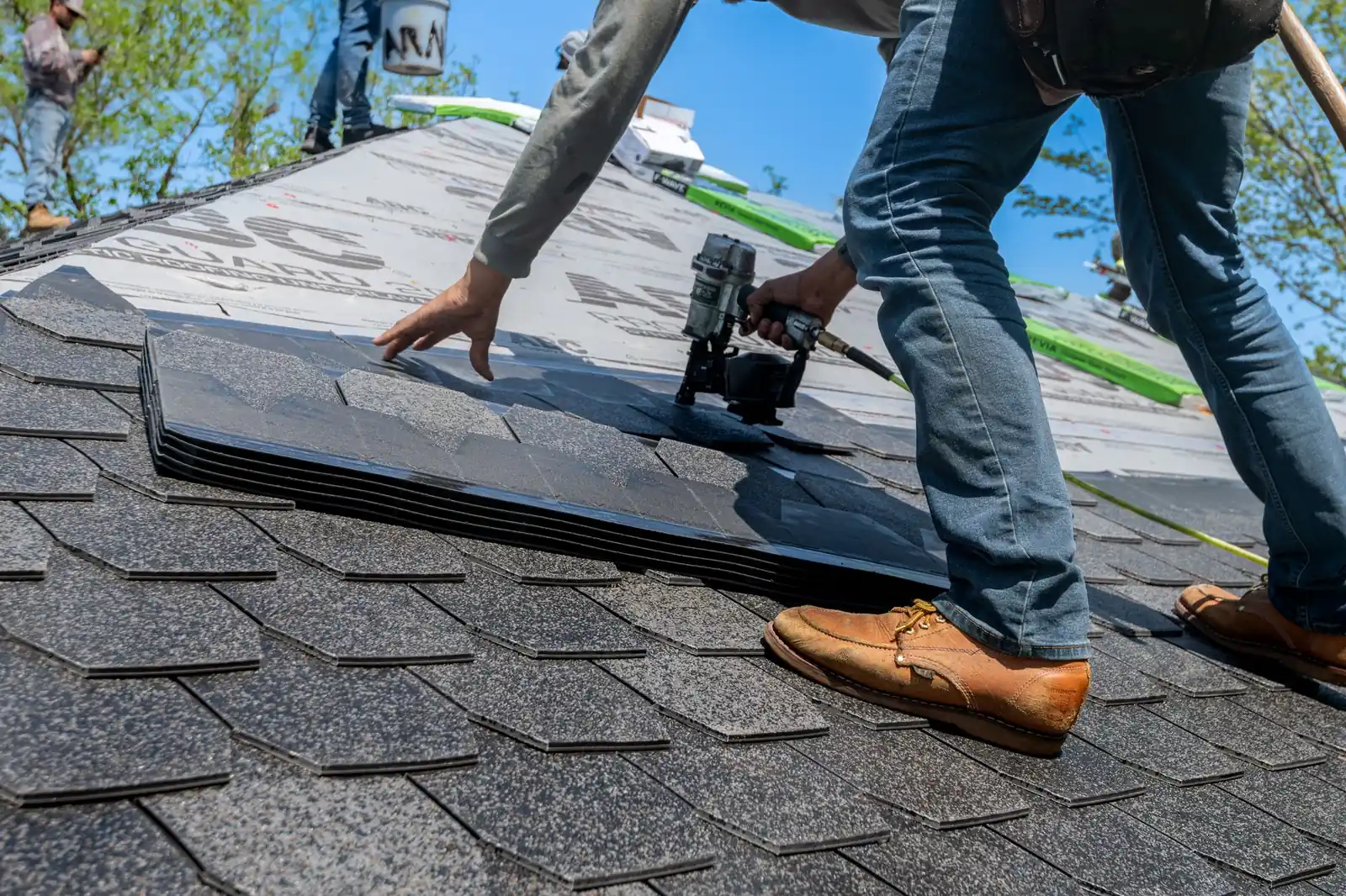 Roofer installing roof tiles with a nail gun on a new roof